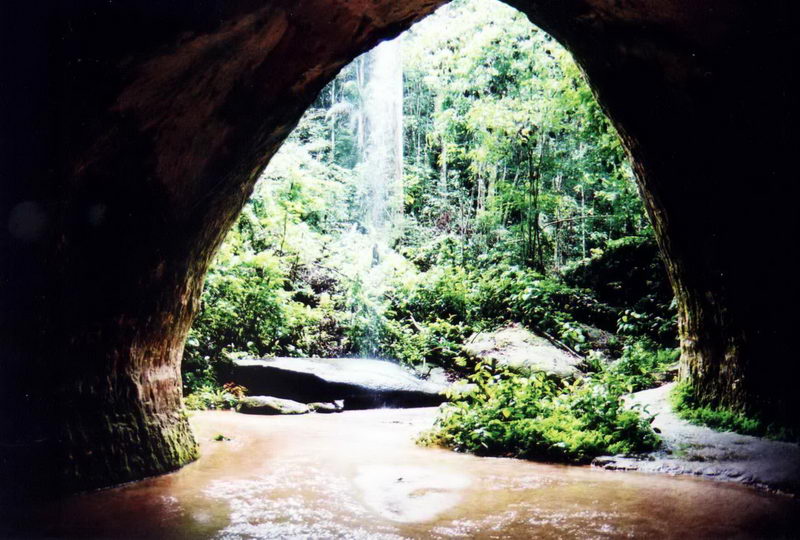 Entrada de uma gruta encoberta por uma pequena cachoeira
